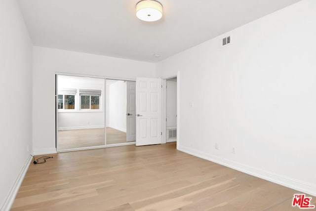 unfurnished bedroom with light hardwood / wood-style floors and a closet