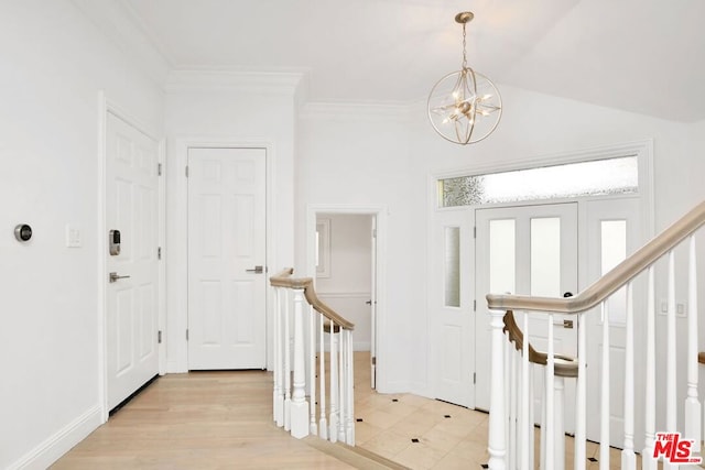 foyer entrance with ornamental molding, light wood-type flooring, and a notable chandelier