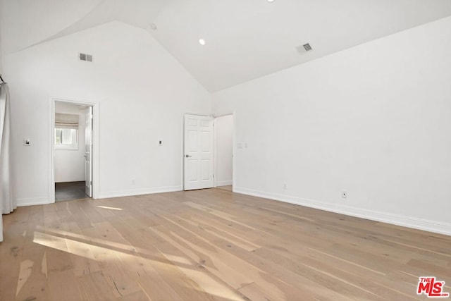 spare room with high vaulted ceiling and light wood-type flooring