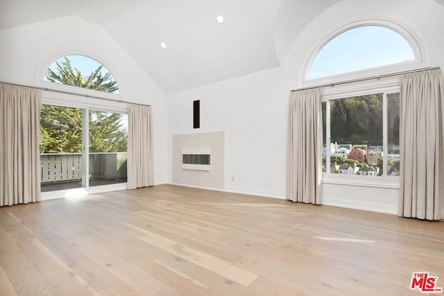 unfurnished living room featuring high vaulted ceiling and light hardwood / wood-style flooring