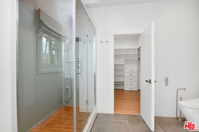 bathroom with hardwood / wood-style flooring, toilet, and a shower with door