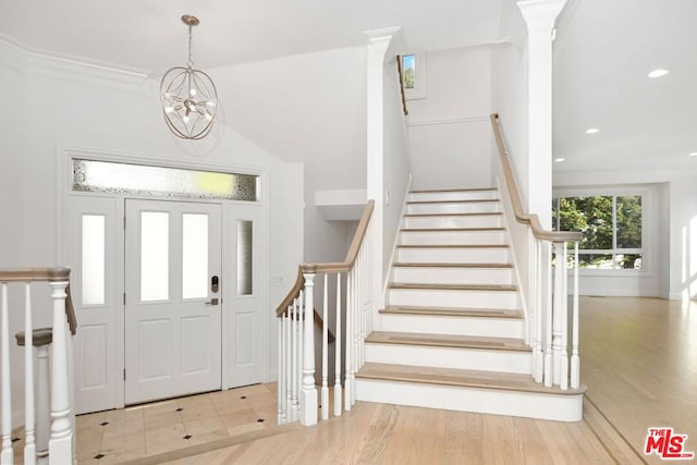 entryway featuring light wood-type flooring, crown molding, and a chandelier