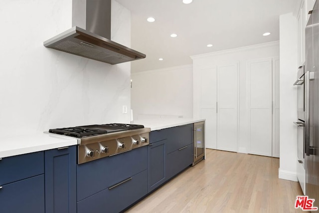 kitchen featuring wall chimney range hood, ornamental molding, light hardwood / wood-style floors, stainless steel appliances, and beverage cooler