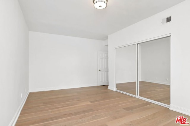 unfurnished bedroom with hardwood / wood-style flooring and a closet