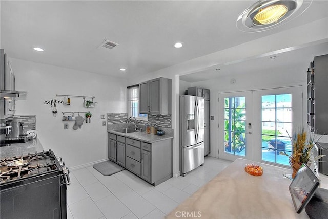 kitchen featuring stainless steel refrigerator with ice dispenser, backsplash, french doors, sink, and gray cabinets