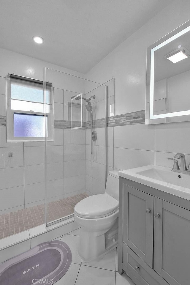 bathroom featuring tile patterned floors, an enclosed shower, toilet, vanity, and tile walls