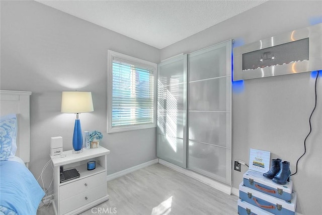 bedroom with a textured ceiling and light hardwood / wood-style flooring