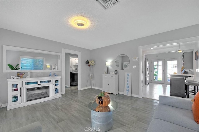 living room featuring ceiling fan, french doors, a textured ceiling, and hardwood / wood-style flooring