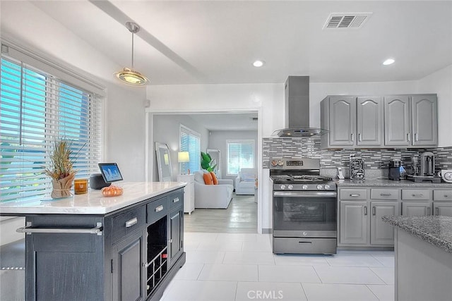 kitchen with gas stove, gray cabinetry, wall chimney exhaust hood, and pendant lighting