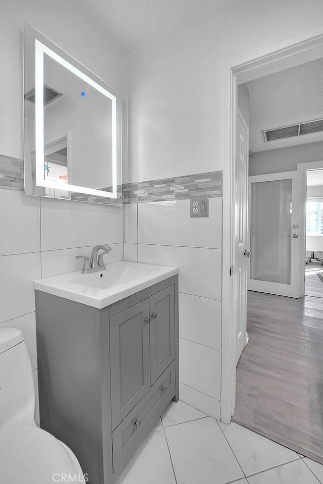 bathroom featuring vanity, toilet, and tile walls