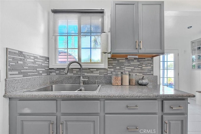 kitchen with gray cabinets, decorative backsplash, and sink