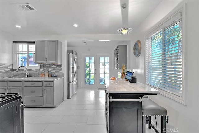 kitchen featuring french doors, tasteful backsplash, sink, stainless steel fridge with ice dispenser, and gray cabinets