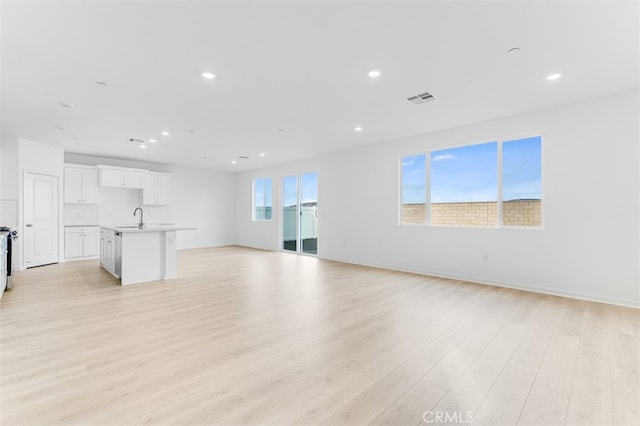 unfurnished living room with visible vents, a sink, light wood-style flooring, and recessed lighting