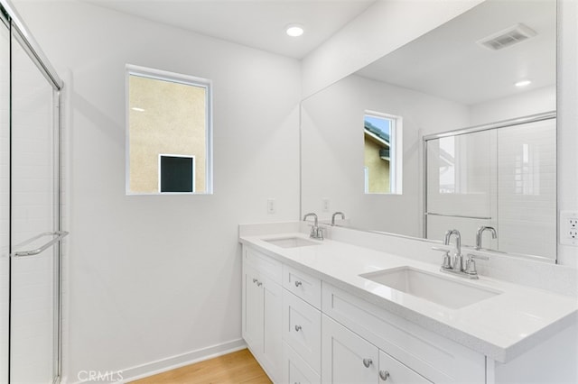 bathroom featuring wood finished floors, a sink, visible vents, and baseboards