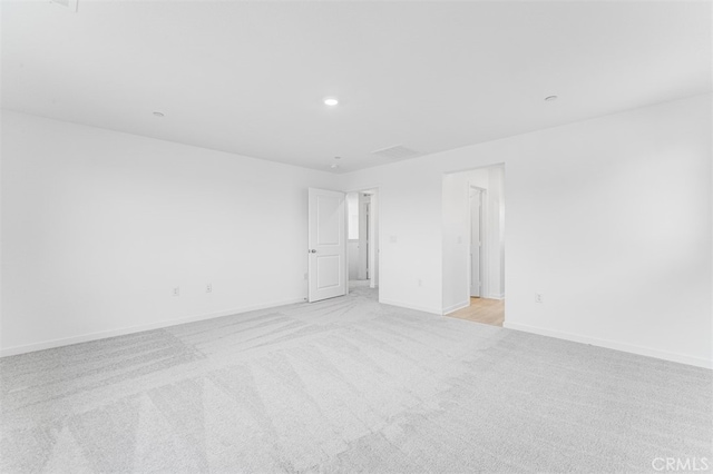 empty room featuring light carpet, baseboards, and recessed lighting