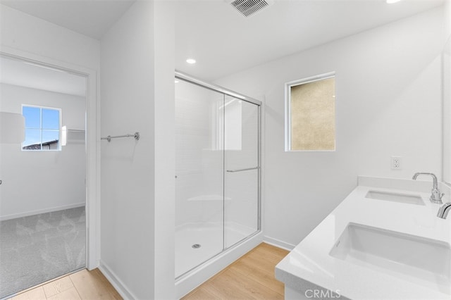 bathroom with a stall shower, baseboards, visible vents, and a sink