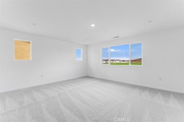 spare room featuring recessed lighting, light colored carpet, visible vents, and baseboards