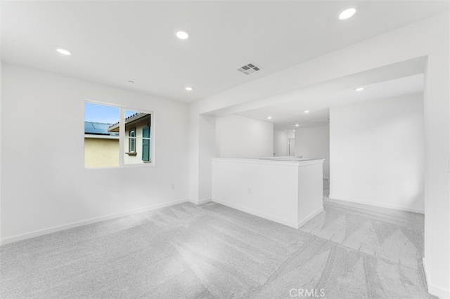 empty room with recessed lighting, light carpet, visible vents, and baseboards