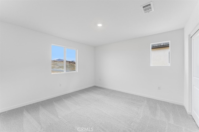 spare room with light colored carpet, visible vents, and baseboards