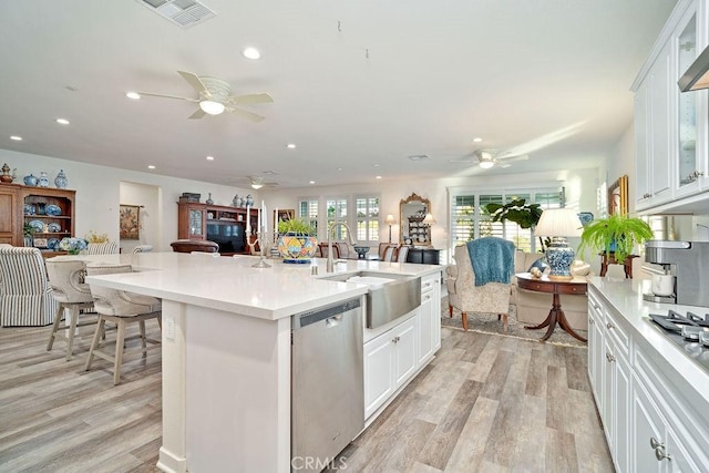 kitchen with white cabinets, light hardwood / wood-style flooring, and stainless steel dishwasher