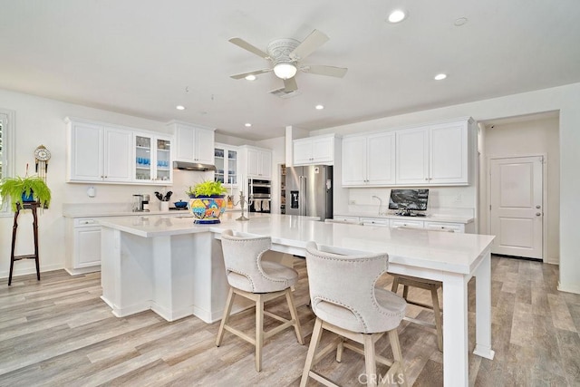 kitchen featuring light hardwood / wood-style flooring, white cabinetry, high end fridge, and a large island