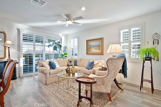 living room featuring ceiling fan, plenty of natural light, and light hardwood / wood-style floors