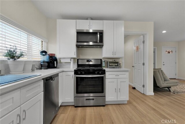 kitchen featuring white cabinets, stainless steel appliances, and light hardwood / wood-style floors