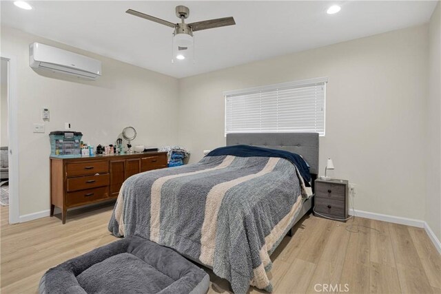 bedroom featuring a wall mounted air conditioner, ceiling fan, and light hardwood / wood-style floors