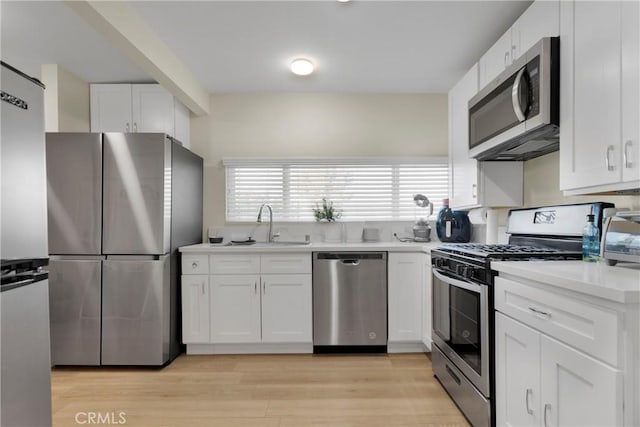 kitchen with appliances with stainless steel finishes, light hardwood / wood-style floors, and white cabinetry