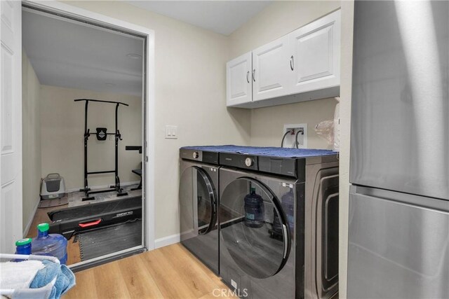 laundry room with separate washer and dryer, light hardwood / wood-style flooring, and cabinets