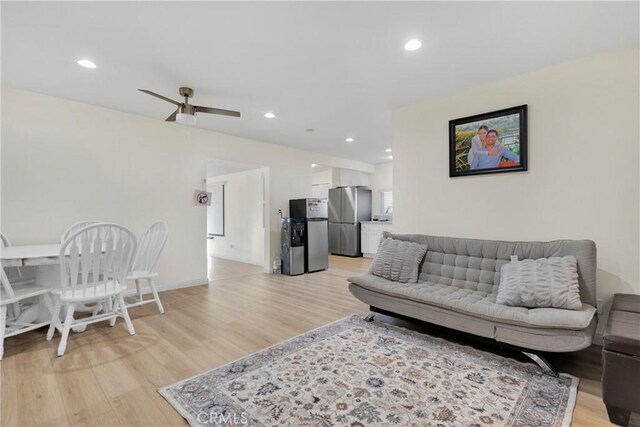 living room featuring ceiling fan and light hardwood / wood-style flooring