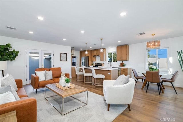 living room with light hardwood / wood-style floors, french doors, and a chandelier