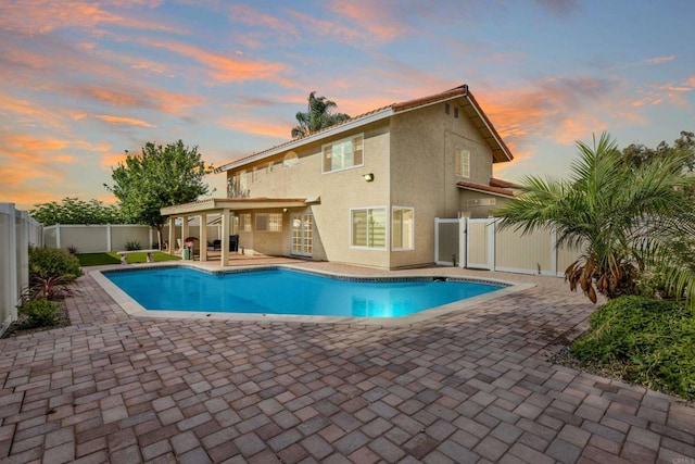 pool at dusk featuring a patio