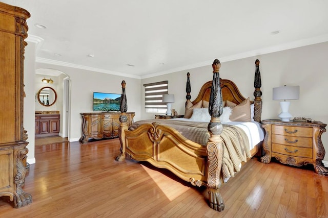 bedroom featuring light wood-type flooring, ornamental molding, and connected bathroom