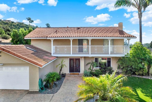 mediterranean / spanish-style home featuring a balcony, a garage, and a front lawn