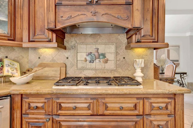 kitchen featuring light stone countertops, backsplash, ornamental molding, custom range hood, and stainless steel gas stovetop