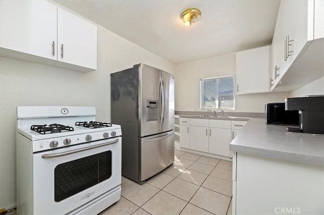 kitchen with sink, stainless steel fridge, light tile patterned floors, gas range gas stove, and white cabinetry