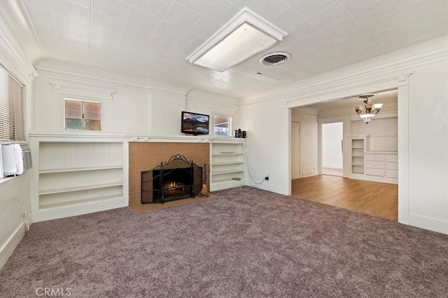 unfurnished living room featuring a fireplace, carpet, crown molding, and a notable chandelier