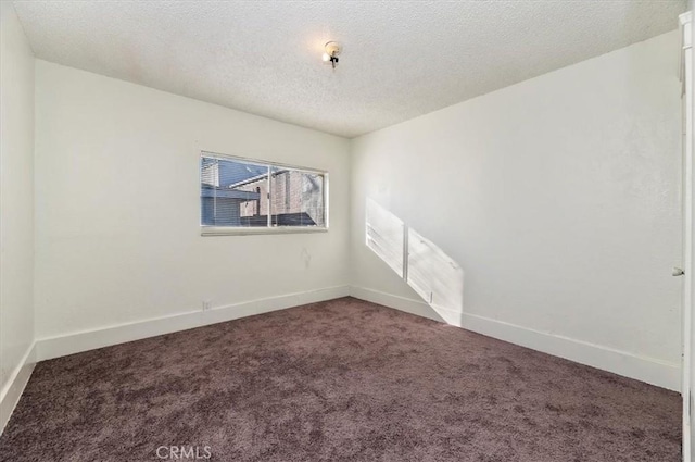 carpeted empty room featuring a textured ceiling