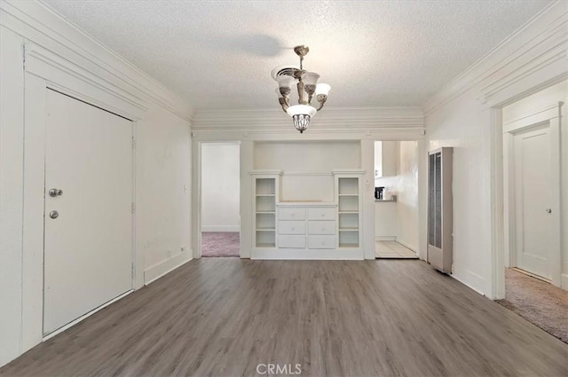 unfurnished living room featuring ornamental molding, a textured ceiling, an inviting chandelier, and dark wood-type flooring