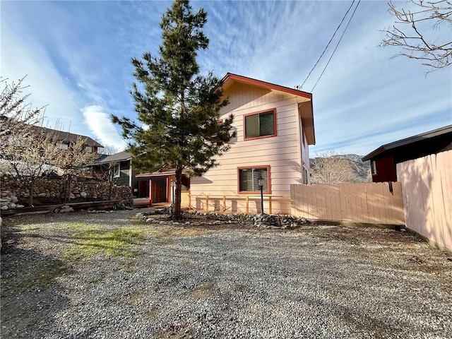 rear view of house with gravel driveway and fence