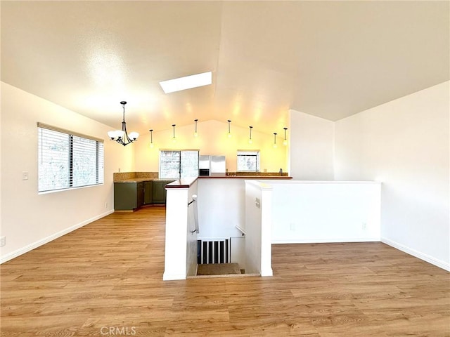 kitchen featuring light wood-style flooring, stainless steel refrigerator with ice dispenser, decorative light fixtures, vaulted ceiling with skylight, and an inviting chandelier