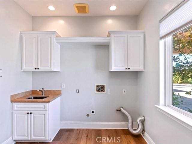 laundry area with electric dryer hookup, sink, hardwood / wood-style flooring, and a healthy amount of sunlight