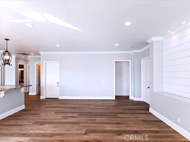 unfurnished living room with ornamental molding, dark hardwood / wood-style floors, and a chandelier