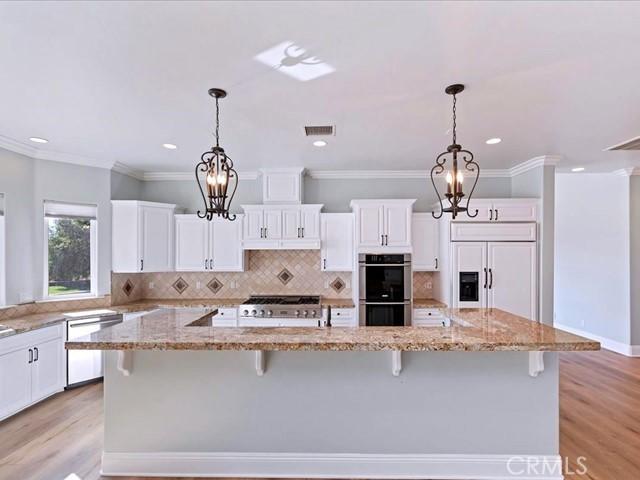 kitchen with paneled refrigerator, a kitchen breakfast bar, dishwasher, stainless steel double oven, and a large island