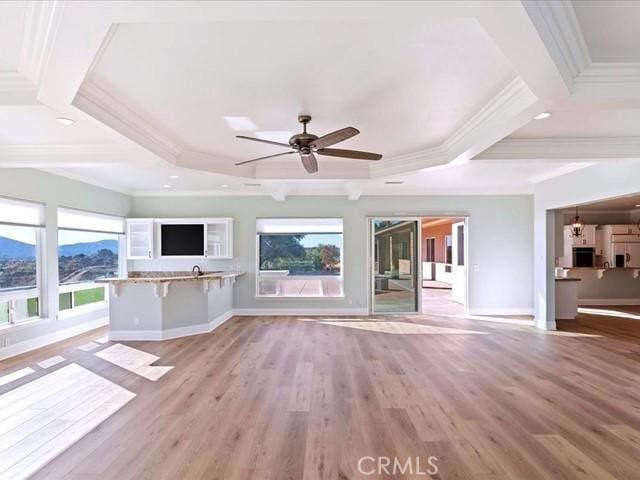 unfurnished living room featuring beamed ceiling, a wealth of natural light, and light wood-type flooring