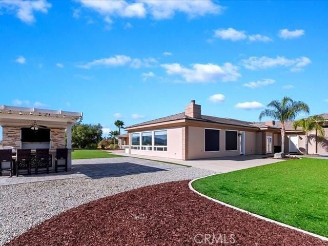 rear view of house with ceiling fan, a yard, and a patio area