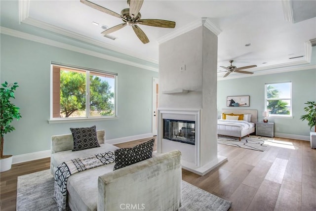 living room featuring crown molding, a multi sided fireplace, ceiling fan, and hardwood / wood-style floors