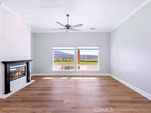 unfurnished living room with hardwood / wood-style flooring, ornamental molding, and ceiling fan