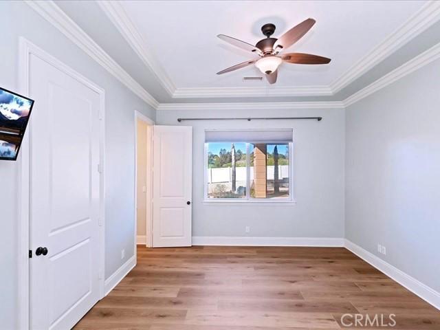 unfurnished bedroom with ceiling fan, ornamental molding, and light wood-type flooring